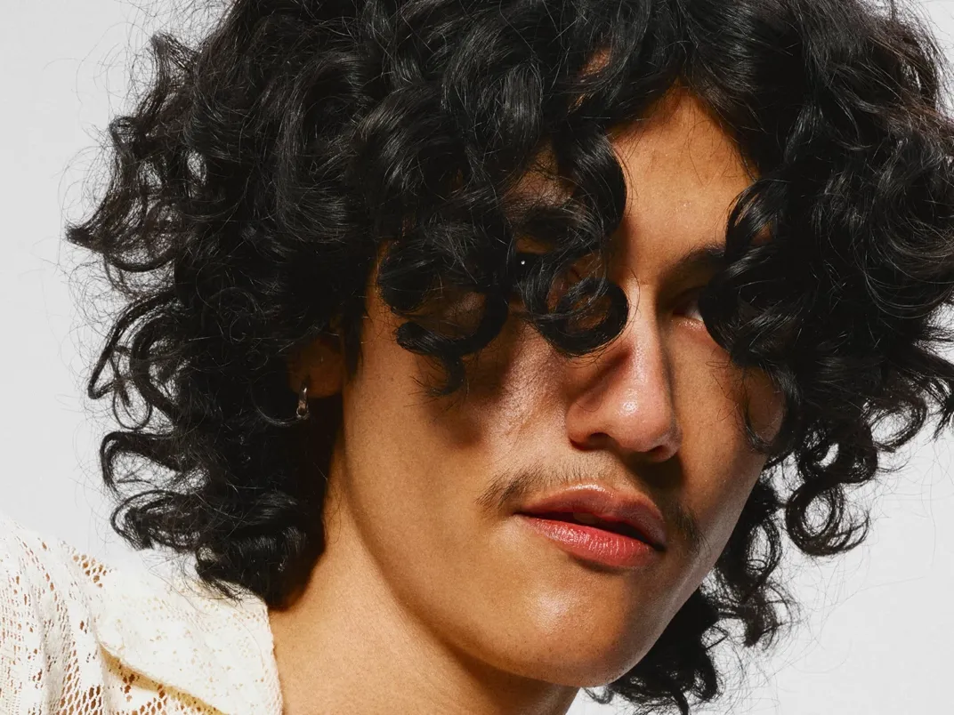 Man med stort svart lockigt hår i ansiktet.