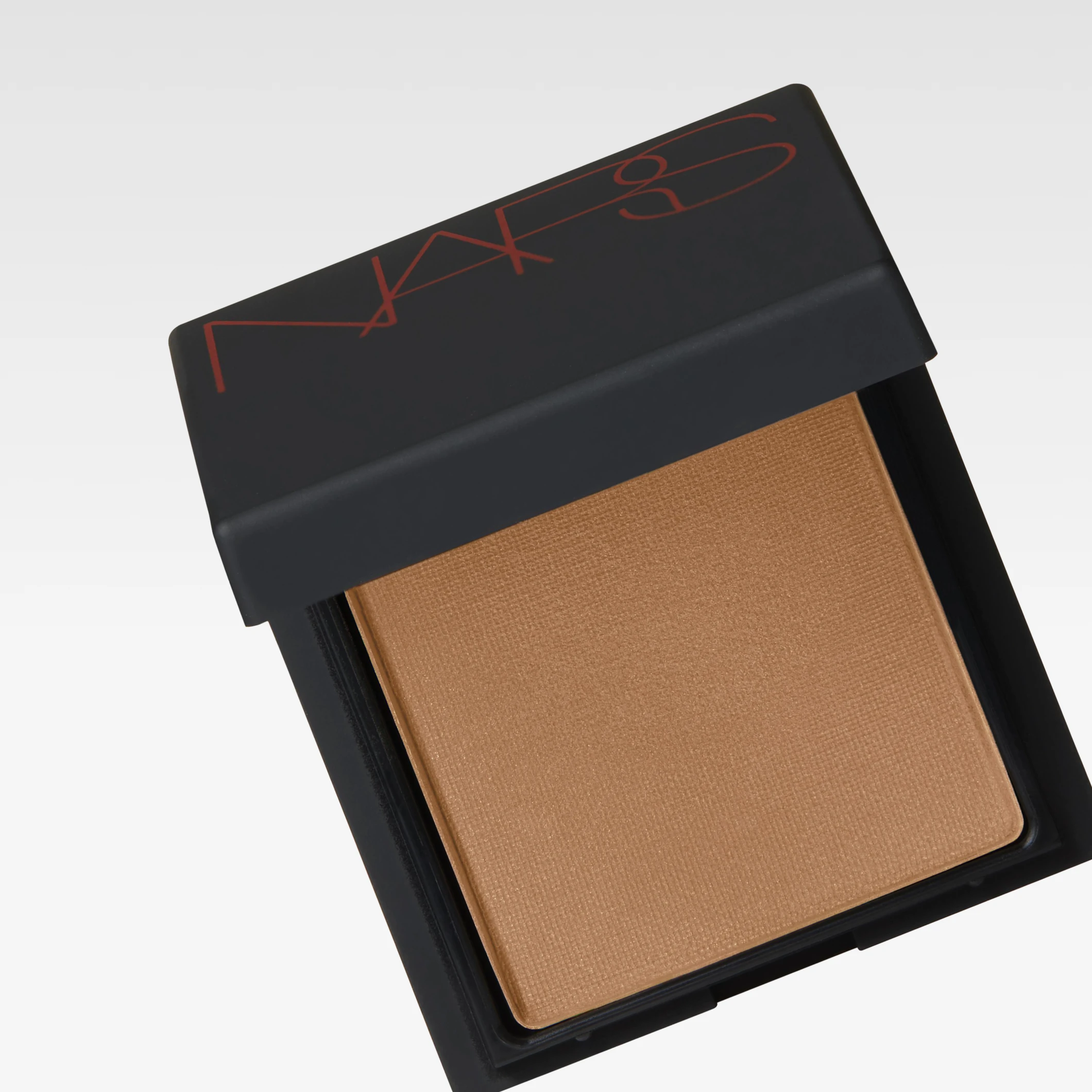 NARS bronzer i svart kompakt dosa med röd logotyp “NARS” på locket och bronzingpuder i varm brun nyans.