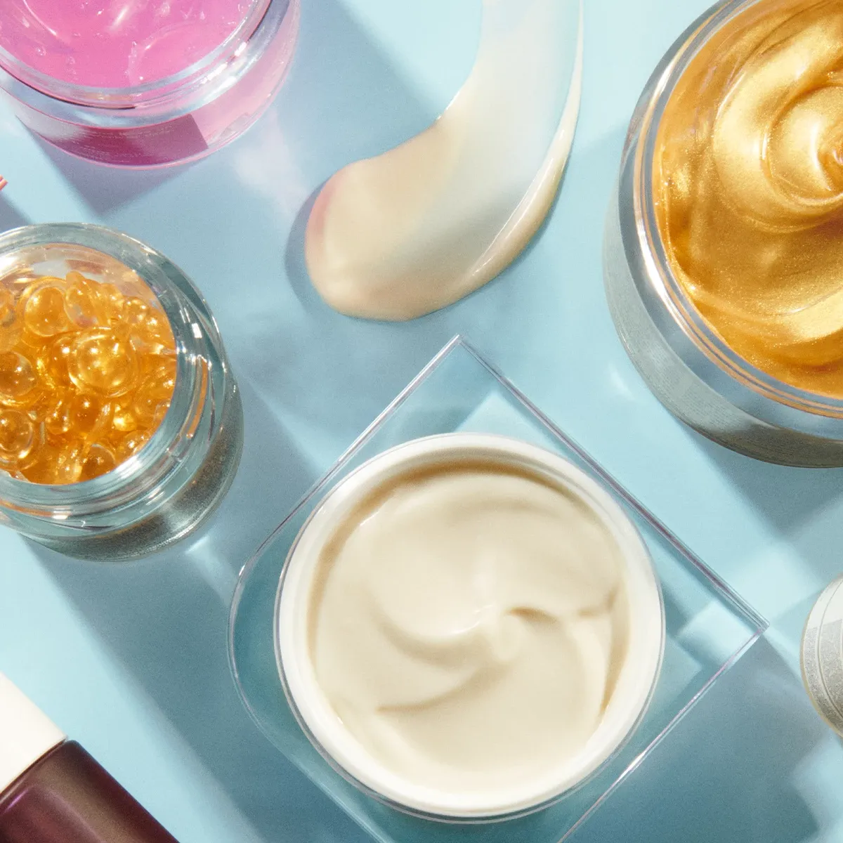 Olika skincareprodukter på ett blått underlag.