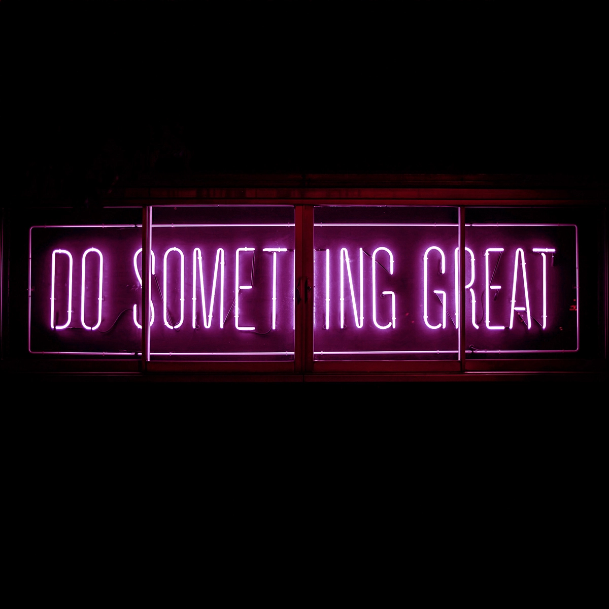Rosa neonskylt med texten "Do something great"mot mörk bakgrund.