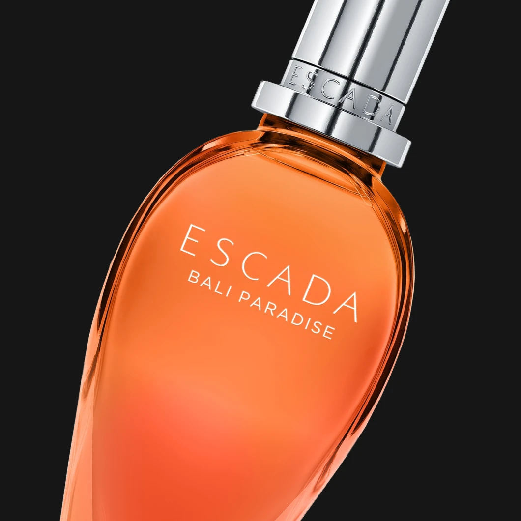 Escada Bali Paradise Eau de Parfum i en orange glasflaska mot svart bakgrund. På flaskan syns texten "ESCADA BALI PARADISE".