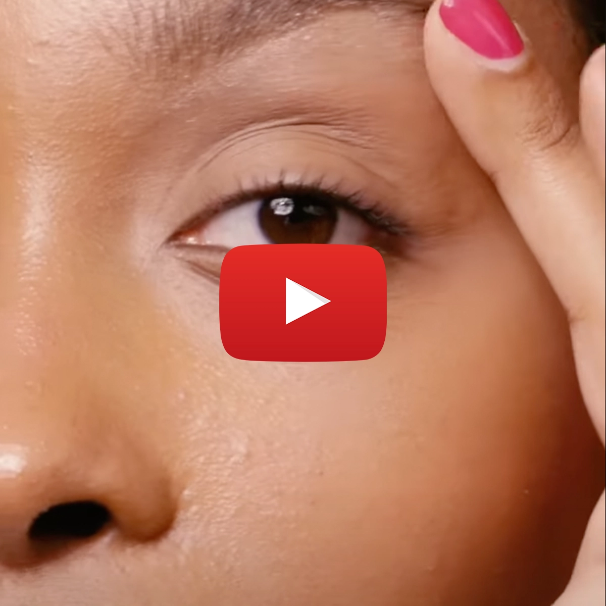 En närbild på en person som applicerar smink på ögonbrynet med en rosa nagel. Ett Youtube play-tecken är placerat i mitten av bilden.