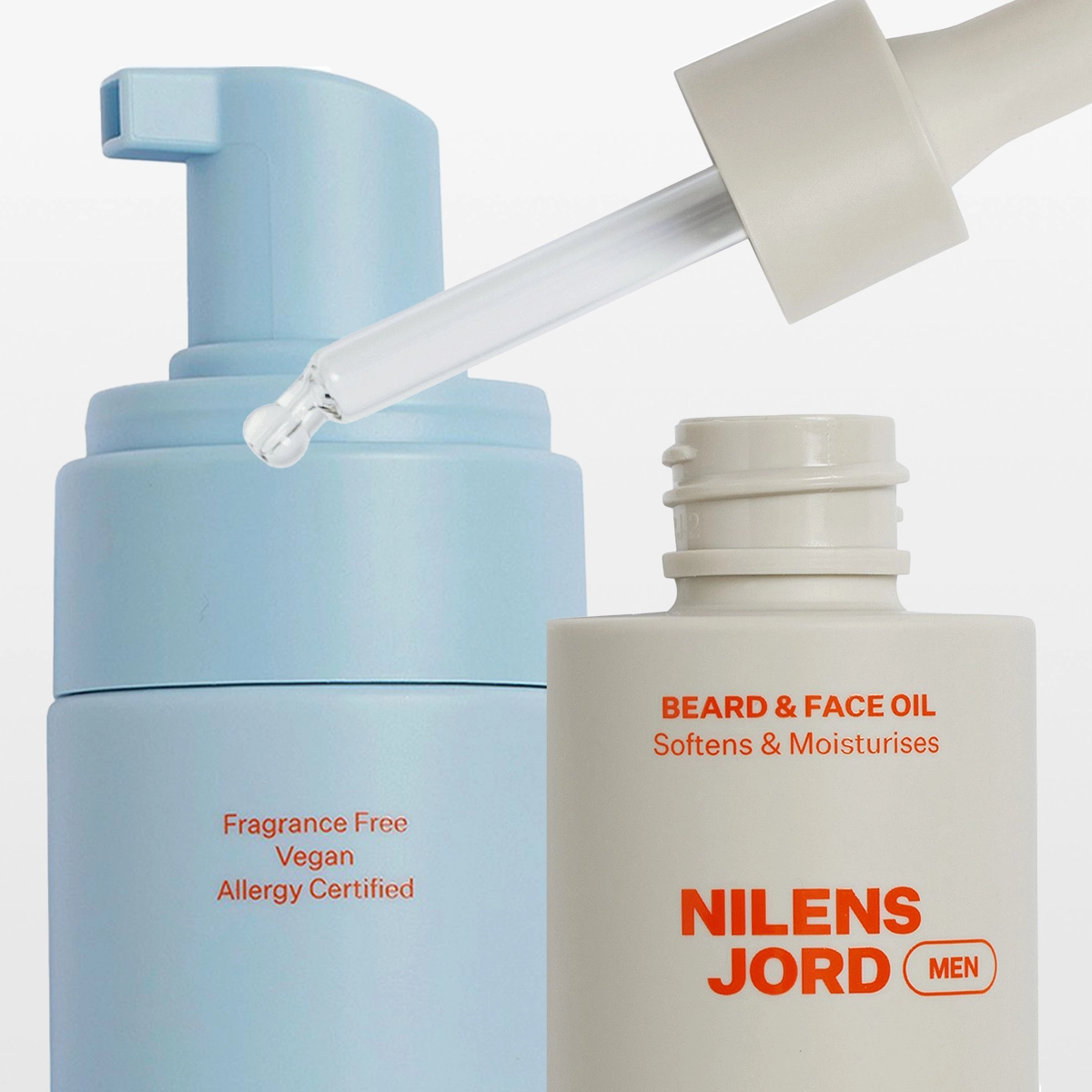 Nilens Jord MEN -ihonhoito- ja groomingtuotteita vaaleaa taustaa vasten, mukana vaahtoputsari, roll-on-tuote ja Beard & Face Oil -öljy pipetillä. Pakkauksissa näkyvät tekstit “Fragrance Free”, “Vegan”, “Allergy Certified”, “BEARD & FACE OIL Softens & Moisturises” ja “NILENS JORD MEN”.