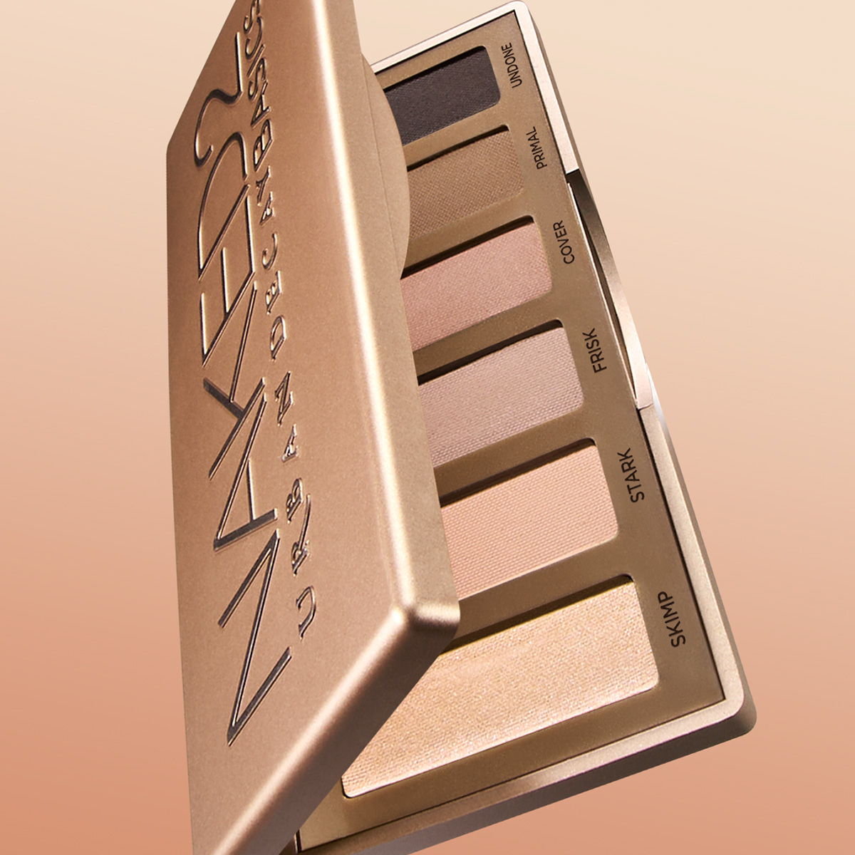 Avoin luomiväripaletti, jossa on kuusi neutraalia sävyä, lepää vaaleanruskealla taustalla. Paletissa lukee "NAKED 2 URBAN DECAY BASICS".
