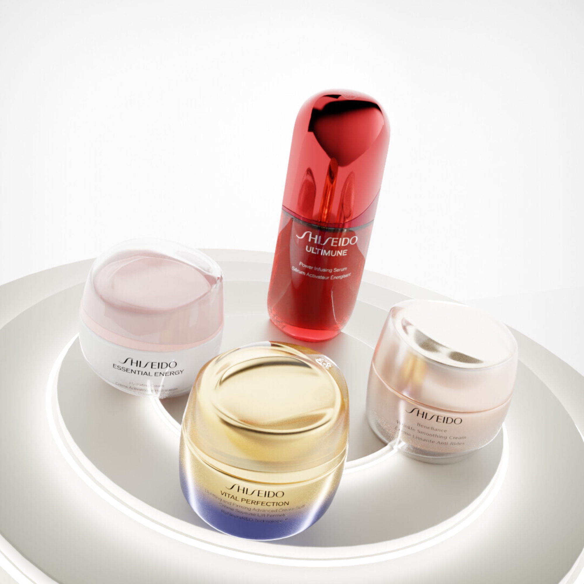 Useita Shiseido-ihonhoitotuotteita, kuten seerumi ja voiteita, aseteltuna pyöreälle alustalle vaaleaa taustaa vasten.