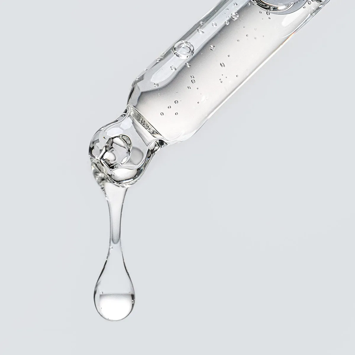 En närbild av en pipett som släpper en droppe klar vätska.