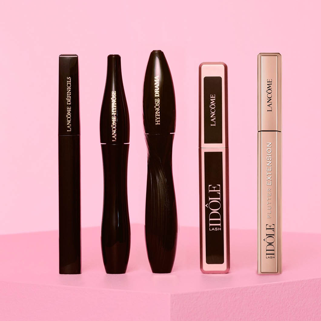 Fem Lancôme-maskaraer står på rad mot rosa bakgrunn.