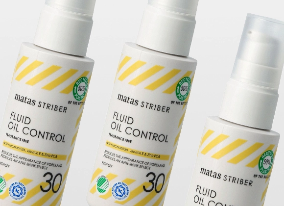 Tre hvite pumpeflasker av Matas Striber Fluid Oil Control plassert skrått mot hverandre med gule diagonale striper og teksten “FRAGRANCE FREE”, “with niacinamide, vitamin E & Zinc PCA” samt “REDUCES THE APPEARANCE OF PORES AND PROVIDES AN ANTI-SHINE EFFECT”. Etiketten viser også “HIGH SPF 30” og symboler for “RECYCLED 50% PLASTIC”, “NORDIC SWAN ECOLABEL” og “ASTHMA ALLERGY NORDIC”.