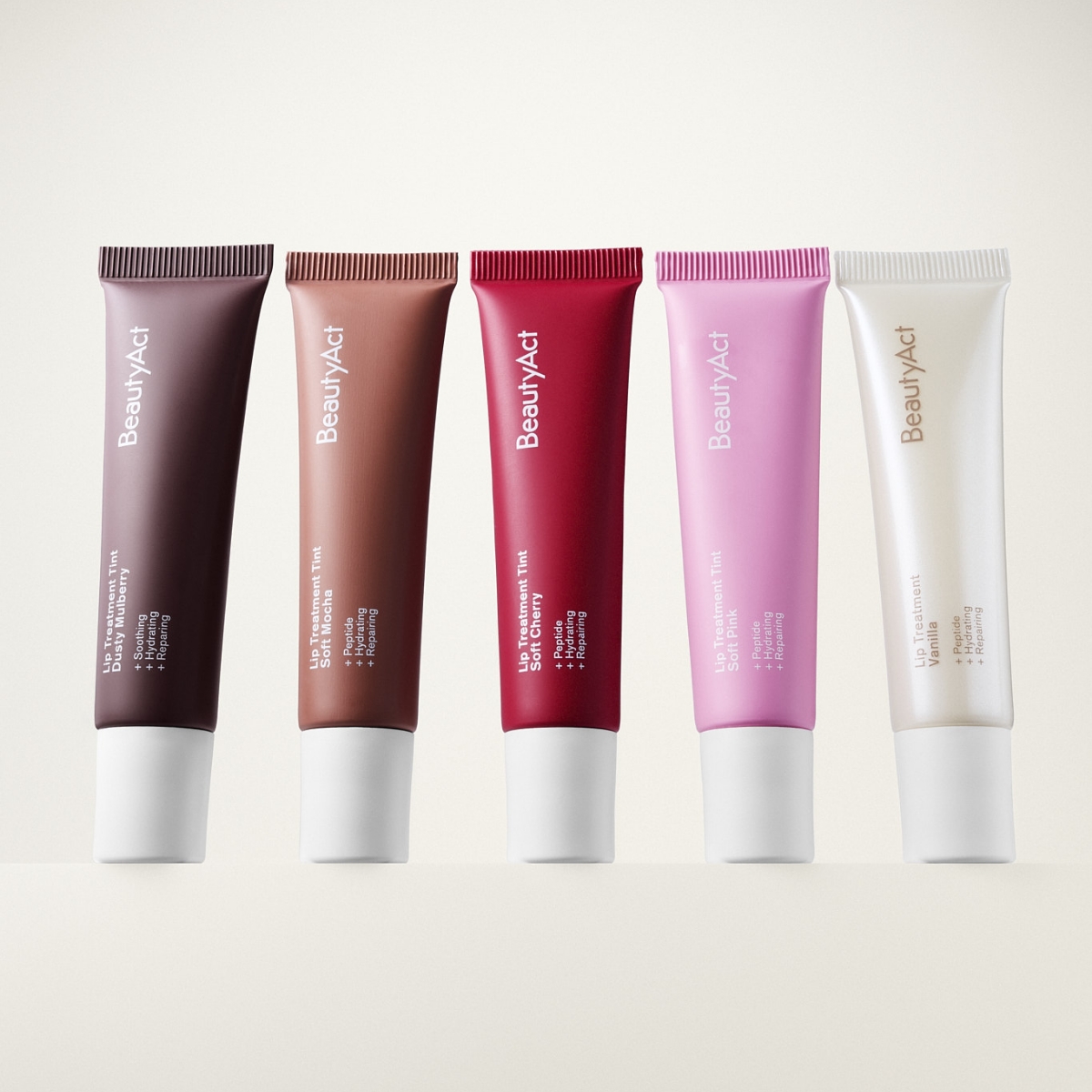 Fem BeautyAct läpprodukter i tub med olika nyanser som brun, nude, röd, rosa och transparent, med synlig text “BeautyAct”, “Lip Treatment Tint” och “SPF 15” på ljus bakgrund.