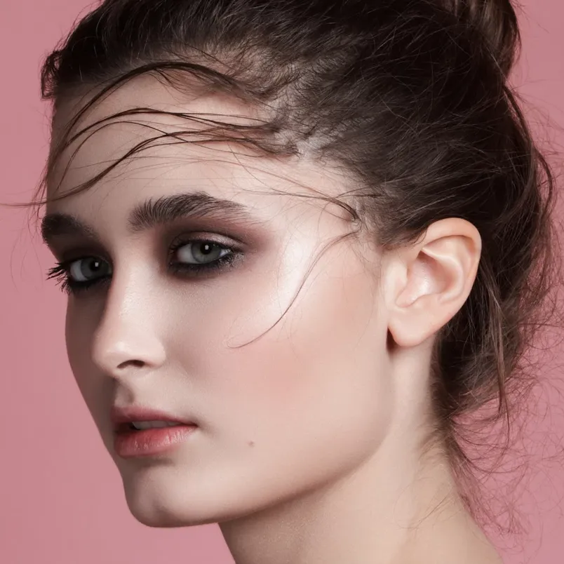 Kvinna med sotad ögonmakeup och löst uppsatt hår.