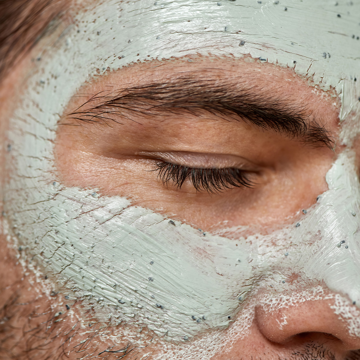 Henkilön kasvot silmät suljettuina, otsaan, nenään ja poskiin levitetty vihreä savikasvonaamio.