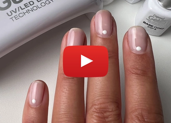 Hand med glänsande nude-rosa naglar, var och en med en liten vit prick nära nagelbandet.