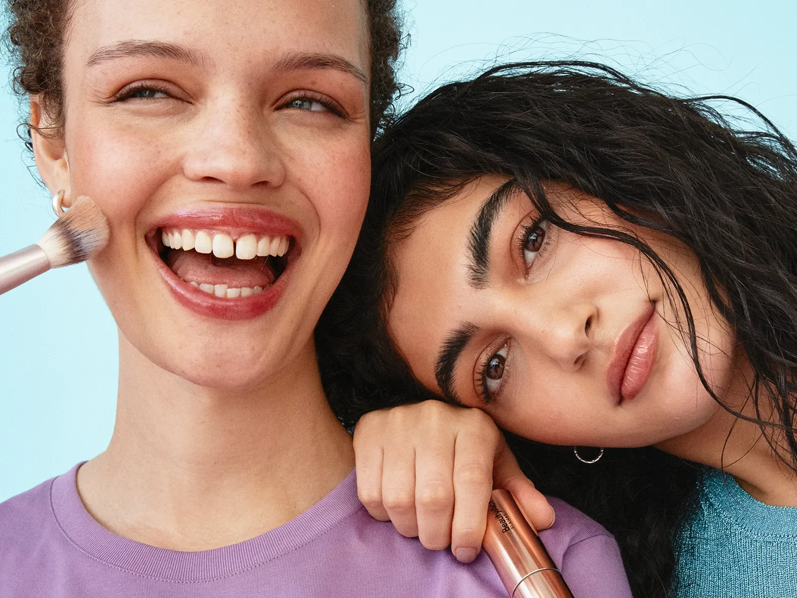 To personer med krøllete hår holder sminkebørster.