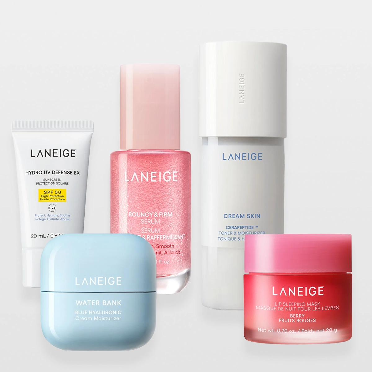 Produktbilde med flere hudpleieprodukter fra Laneige plassert mot lys bakgrunn. Bildet viser en hvit tube merket “Laneige Hydro UV Defense EX SPF 50”, en lyseblå krukke merket “Laneige Water Bank Blue Hyaluronic Cream Moisturizer”, en rosa flaske merket “Laneige Bouncy & Firm Serum”, en hvit flaske merket “Laneige Cream Skin Cerapeptide Toner & Moisturizer” samt en rosa krukke merket “Laneige Lip Sleeping Mask Berry”.