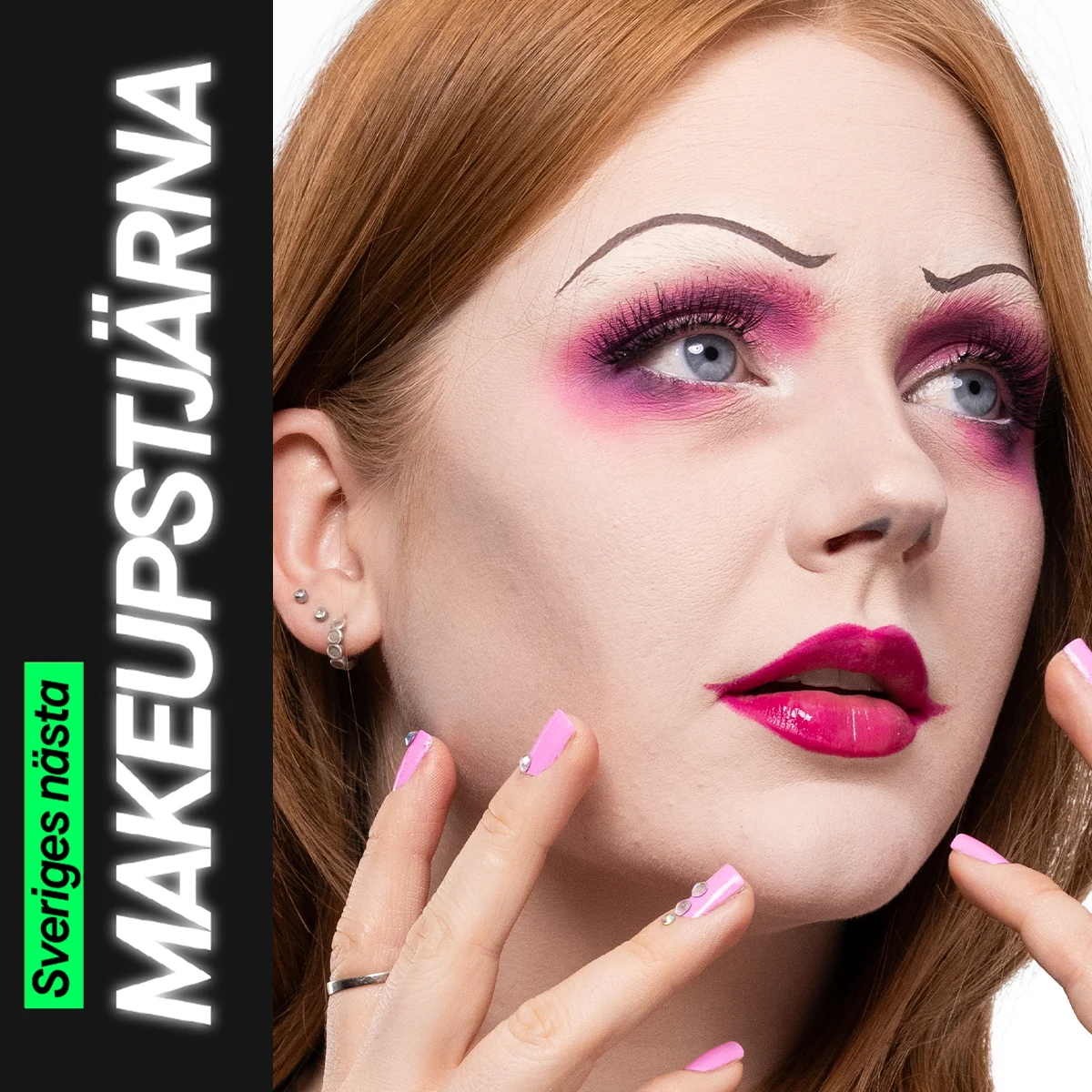 En person med en kreativ makeuplook i rosa toner, med markerad ögonmakeup, långa fransar, skarpt målade tunna ögonbryn och glansiga ceriserosa läppar, där händerna med rosa naglar ramas in omkring ansiktet.
