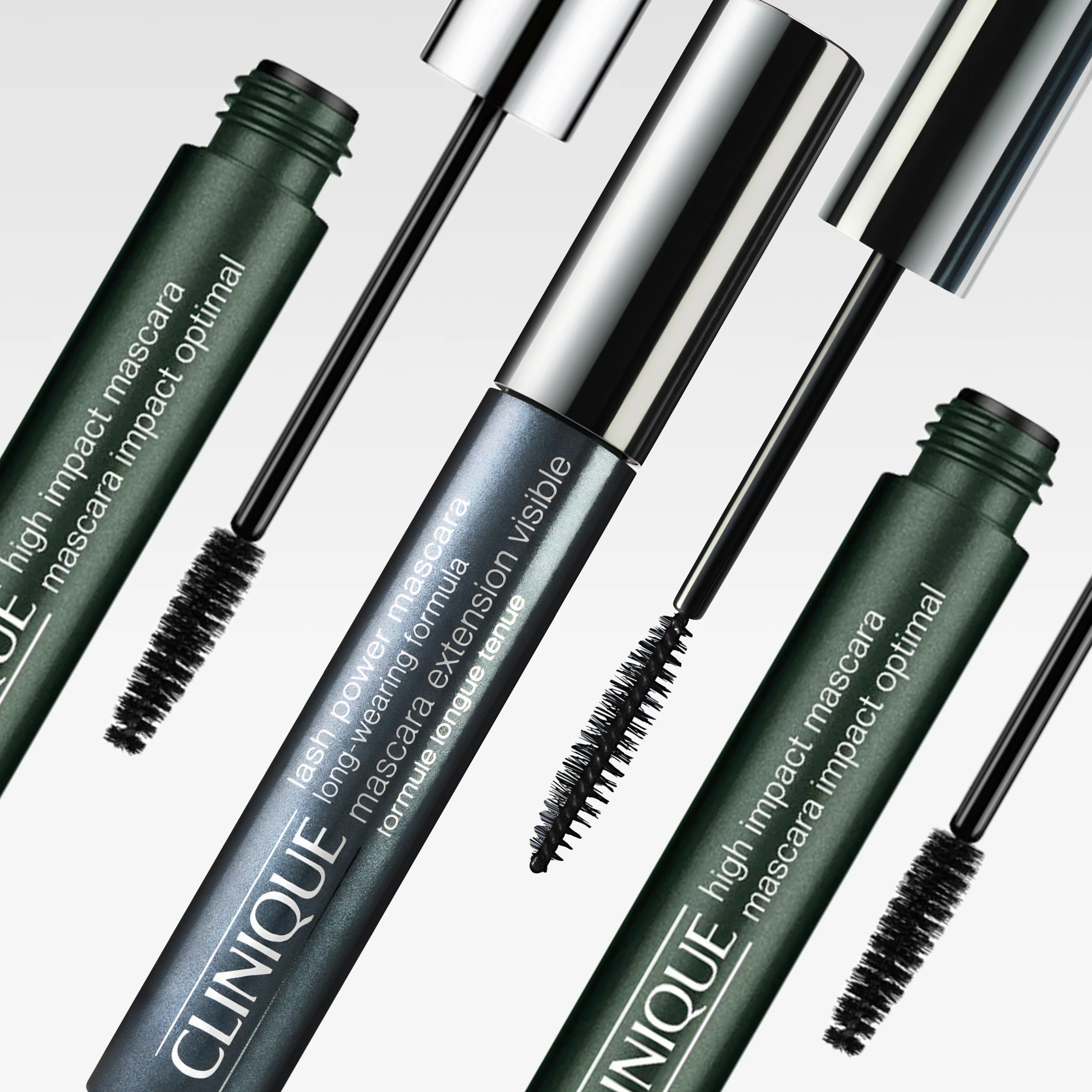 Clinique mascara i gröna och silverfärgade förpackningar med öppna mascaraborstar mot ljusgrå bakgrund. Synlig text inkluderar “high impact mascara”, “lash power mascara long-wearing formula” och “mascara extension visible”.