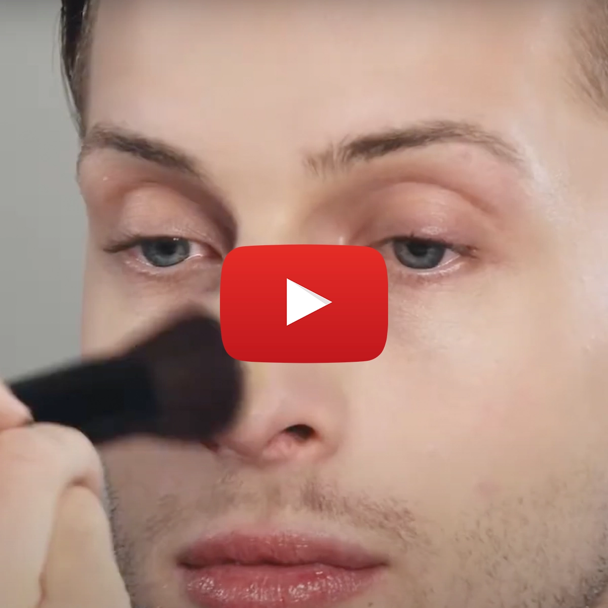 Bild på en person som för en makeup borste över näsan. Med en YouTube-spelknapp över.