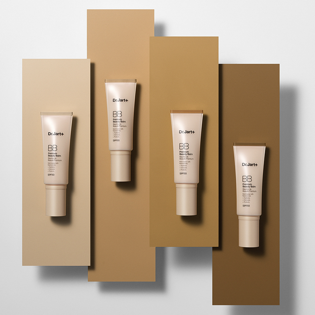 Fire tuber med Dr.Jart+ BB Beauty Balm SPF 50, plassert på forskjellige nyanser av beige og brun bakgrunn.