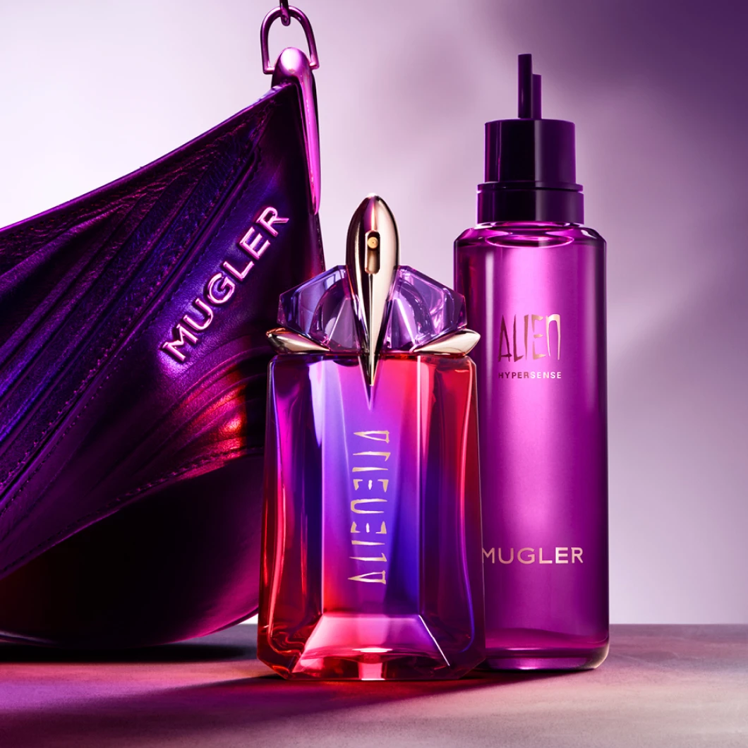 Mugler Alien Eau de Parfum och Alien Hypersense visas framför en lila Mugler-väska. På produkterna syns texterna "ALIEN", "ALIEN HYPERSENSE" och "MUGLER" mot en lila bakgrund.