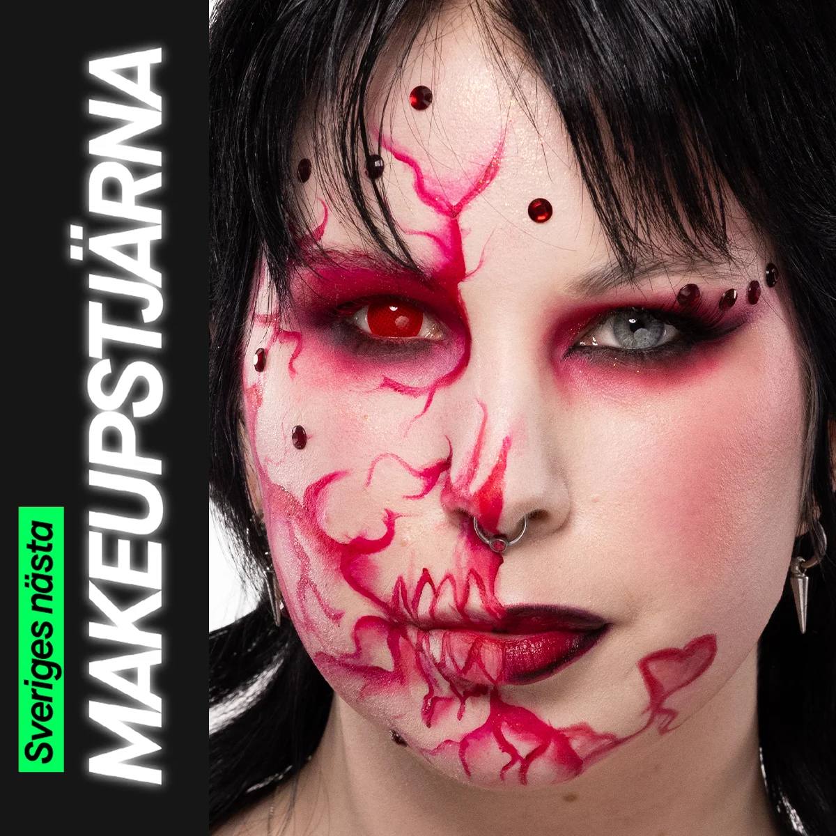 Porträtt av en person med svart hår och kreativ makeup där ansiktet är målat med röda linjer, mönster och dekorativa detaljer, fotograferad mot ljus bakgrund.