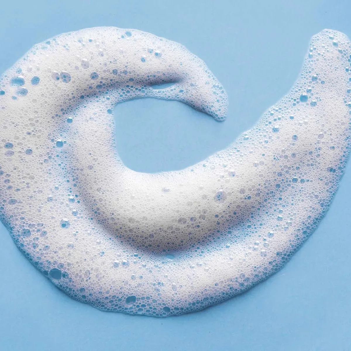 Vitt skum med bubblor format som en spiral, mot ett blått underlag.