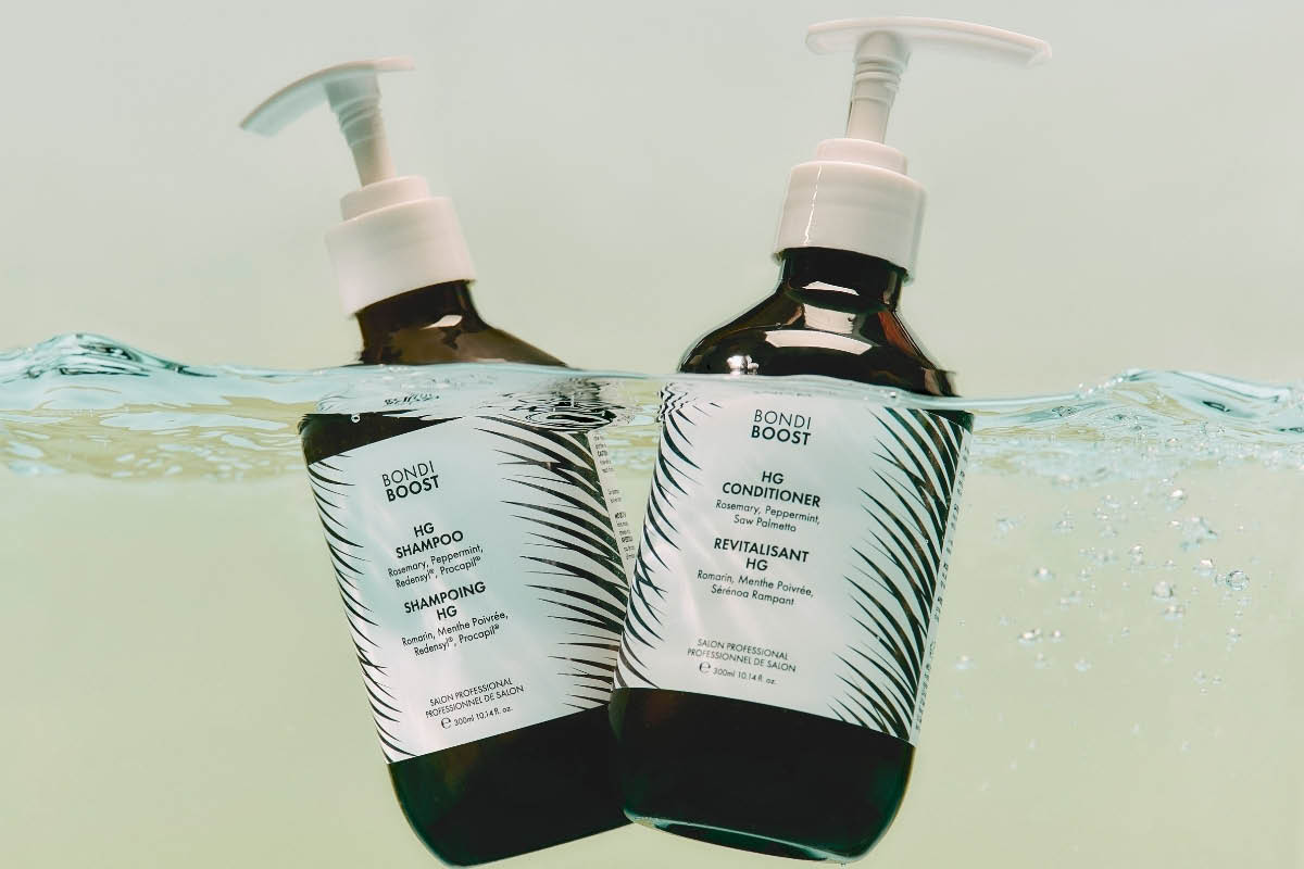 Kaksi pumppupulloa Bondi Boost -tuotteita teksteillä “HG SHAMPOO” ja “HG CONDITIONER”, osittain veden alla. Etiketissä näkyy myös “Rosemary, Peppermint, Redensyl, Procapil” sekä “Salon Professional 300 ml / 10.14 fl oz”.