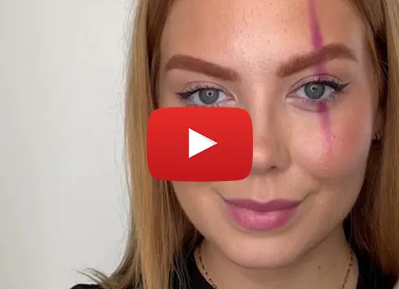 Lähikuva nuoresta naisesta, jolla on pitkä punertavanvaalea tukka ja meikkiä, sekä pystysuuntainen pinkki viiva toisen silmän päällä. Kuvan päällä on YouTube-soitinkuvake.