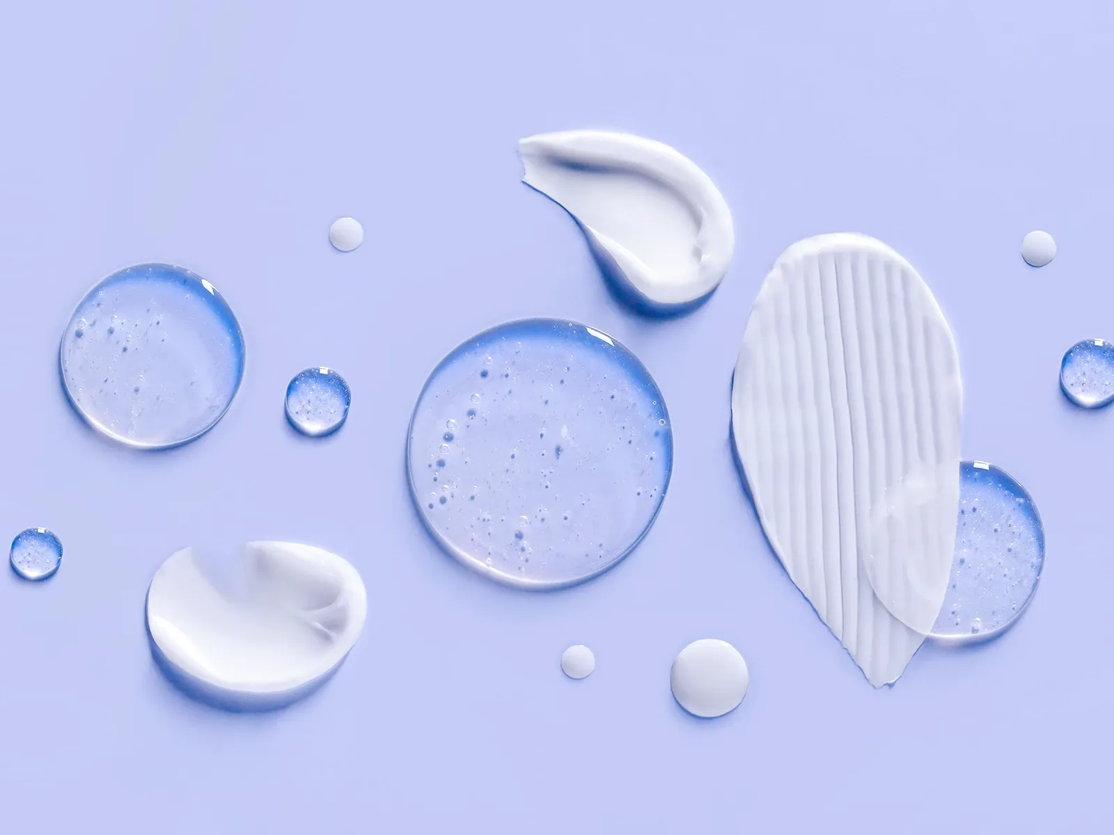  Olika typer av hudvårdsprodukter, inklusive krämer och serum, på en ljusblå bakgrund.