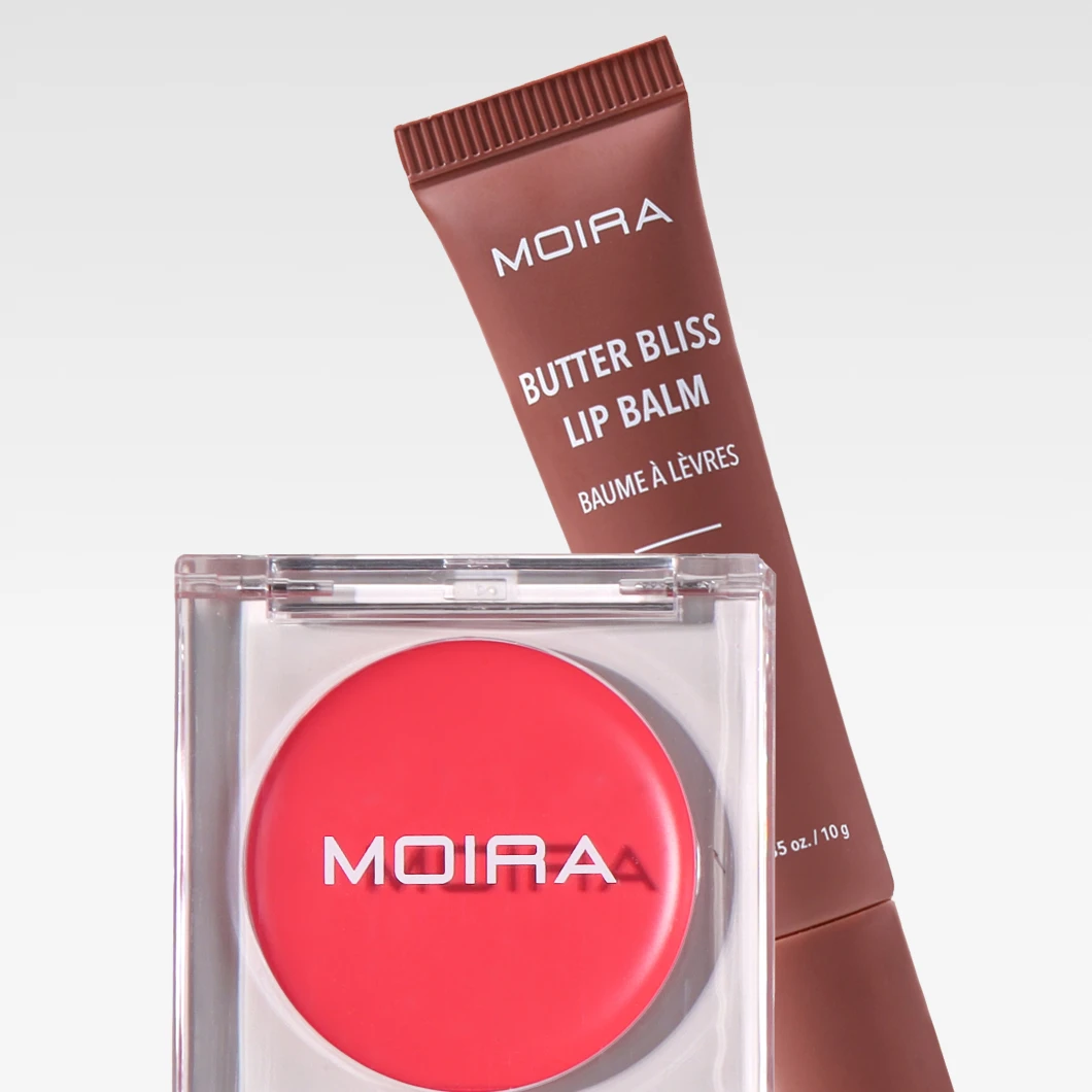 Bilde som viser to Moira produkter: en brun tube med Moira Butter Bliss Lip Balm og en rød boks med Moira blush. Bakgrunnen er hvit.