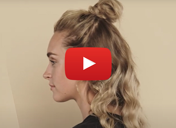Tjej från sidan visar "Half messy bun" mot beige bakgrund.