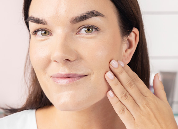 Kvinna med mörkt hår håller handen mot ansiktet