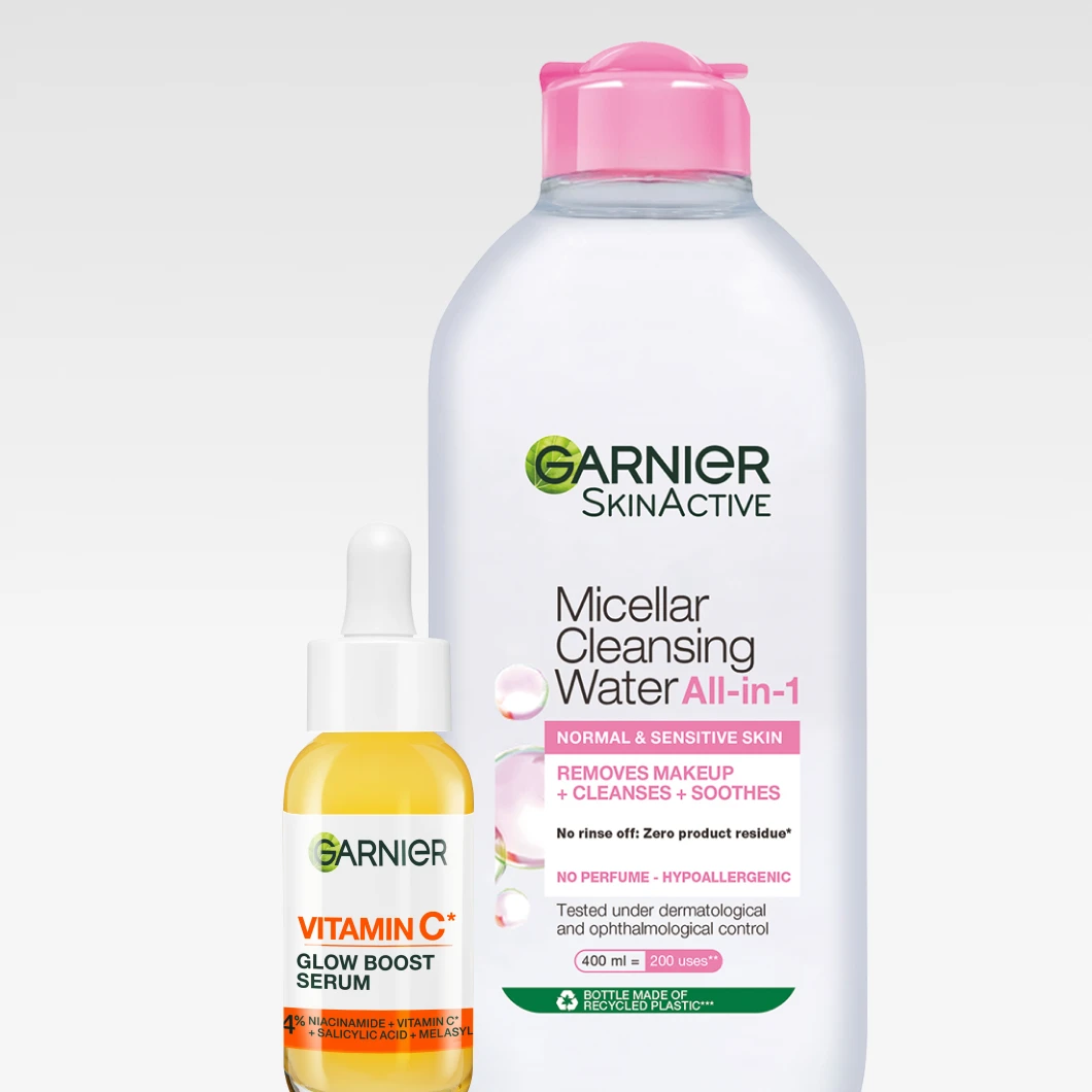 Garnier Vitamin C* Glow Boost Serum står bredvid en stor flaska Micellar Cleansing Water All-in-1 för normal och känslig hud, mot en ljus bakgrund.