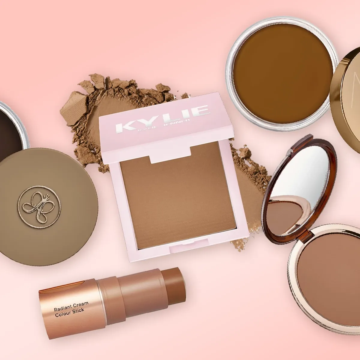 En samling av bronzers og contour-produkter fra forskjellige merker, inkludert Kylie, NARS og Anastasia, plassert på en rosa bakgrunn.
