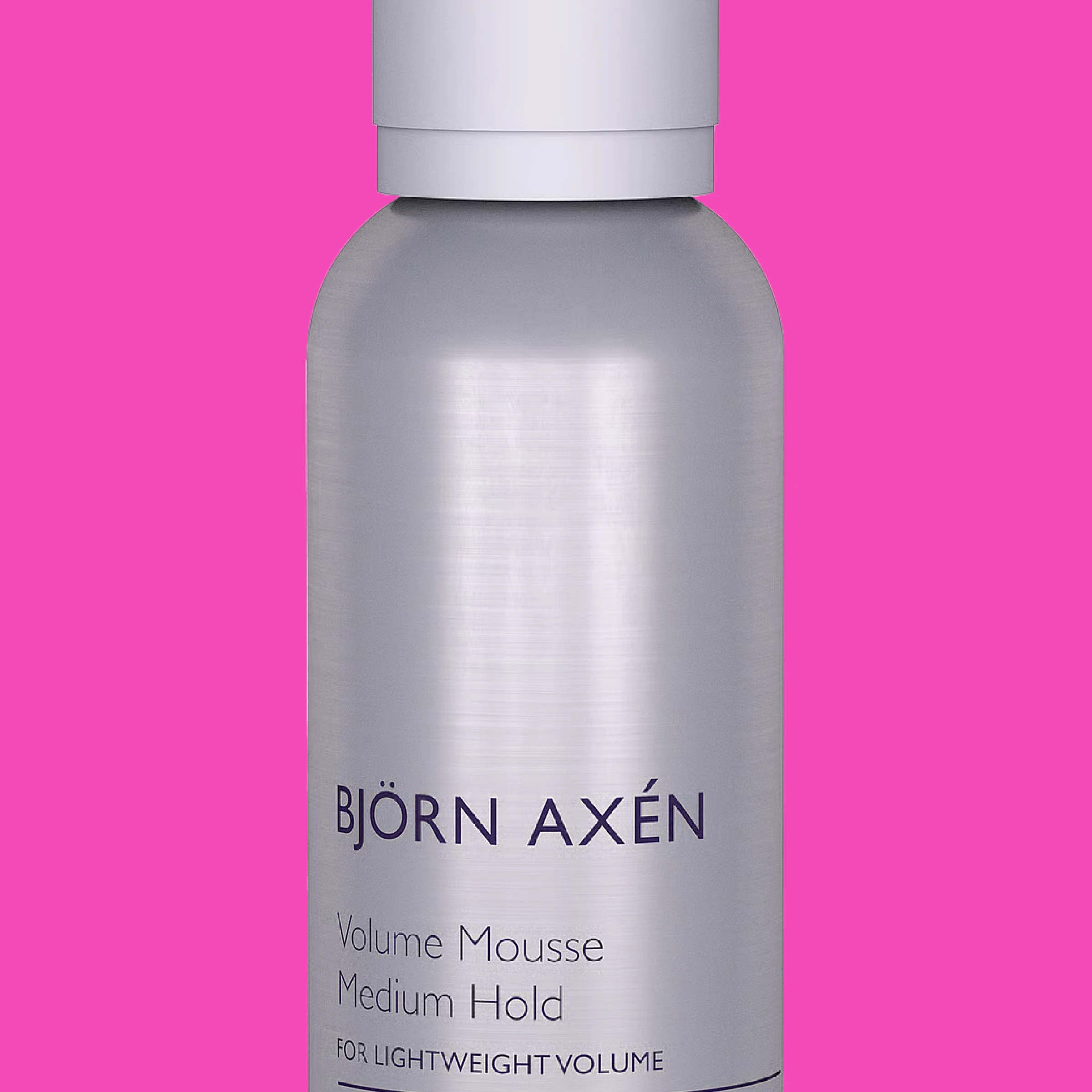 En sølvfarget flaske med Björn Axén Volume Mousse mot en rosa bakgrunn.