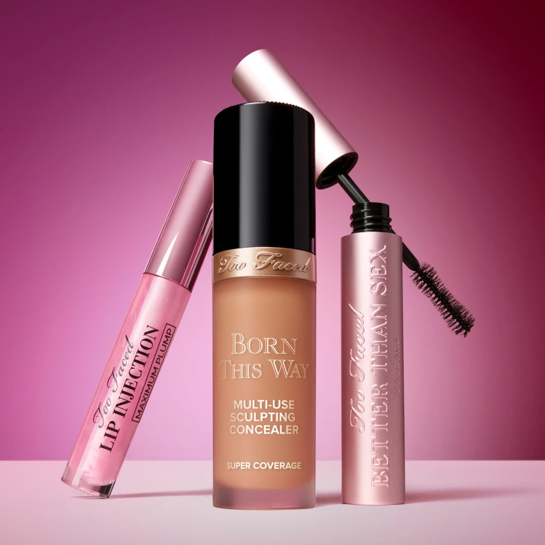 En bild som visar tre produkter från Too Faced. Produkterna inkluderar Lip Injection Maximum Plump, Born This Way Multi-Use Sculpting Concealer och Better Than Sex Mascara. Texten "Stay tuned för yummy makeup!" och "Coming SOON" 