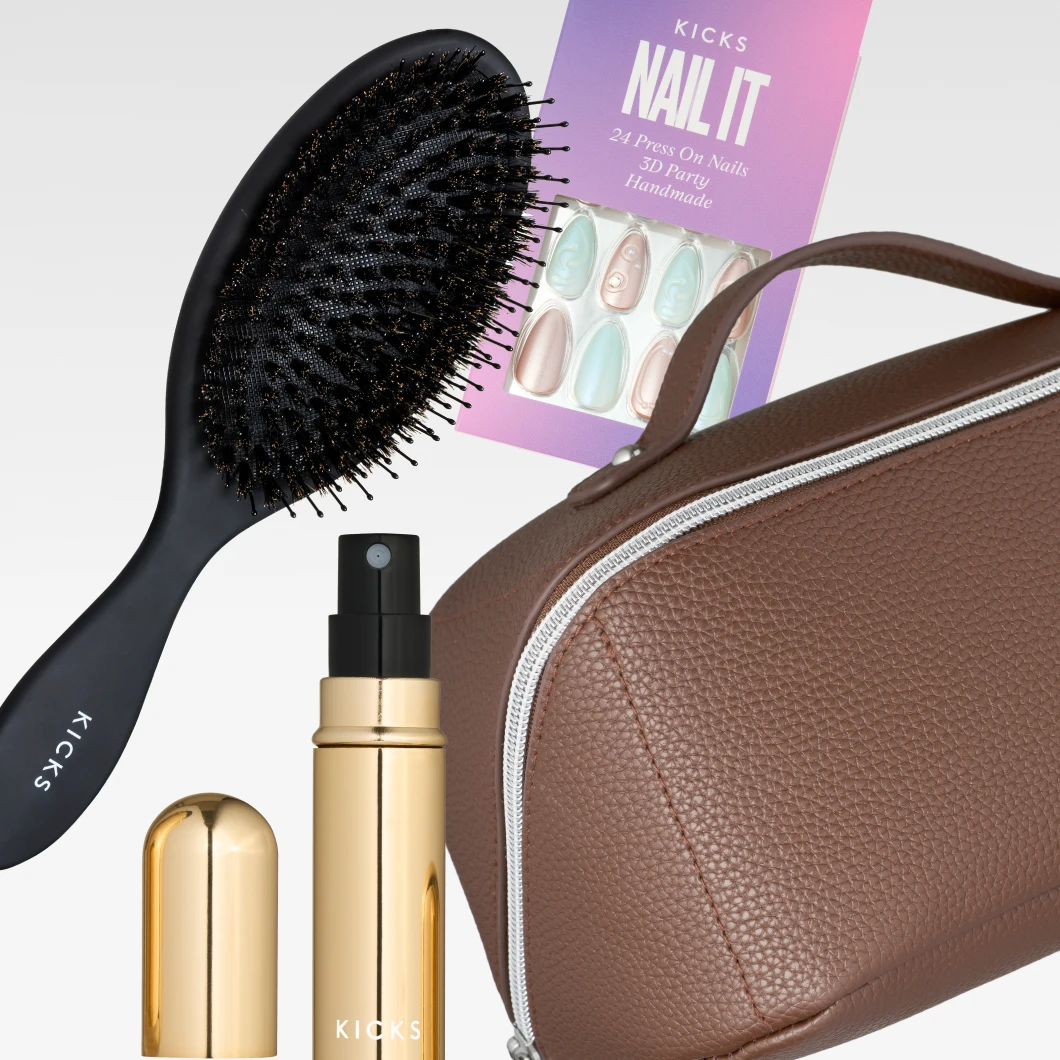 En svart KICKS-hårborste, KICKS Nail It 24 Press On Nails 3D Party Handmade, en guldfärgad KICKS sprayflaska och en brun necessär med dragkedja visas mot en ljusgrå bakgrund.