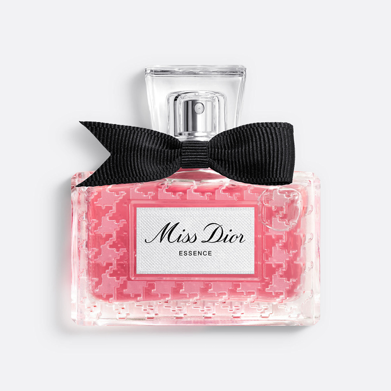 Miss Dior Essence -hajuvesi vaaleanpunaisessa lasipullossa, jossa on musta rusetti ja läpinäkyvä korkki valkoista taustaa vasten.