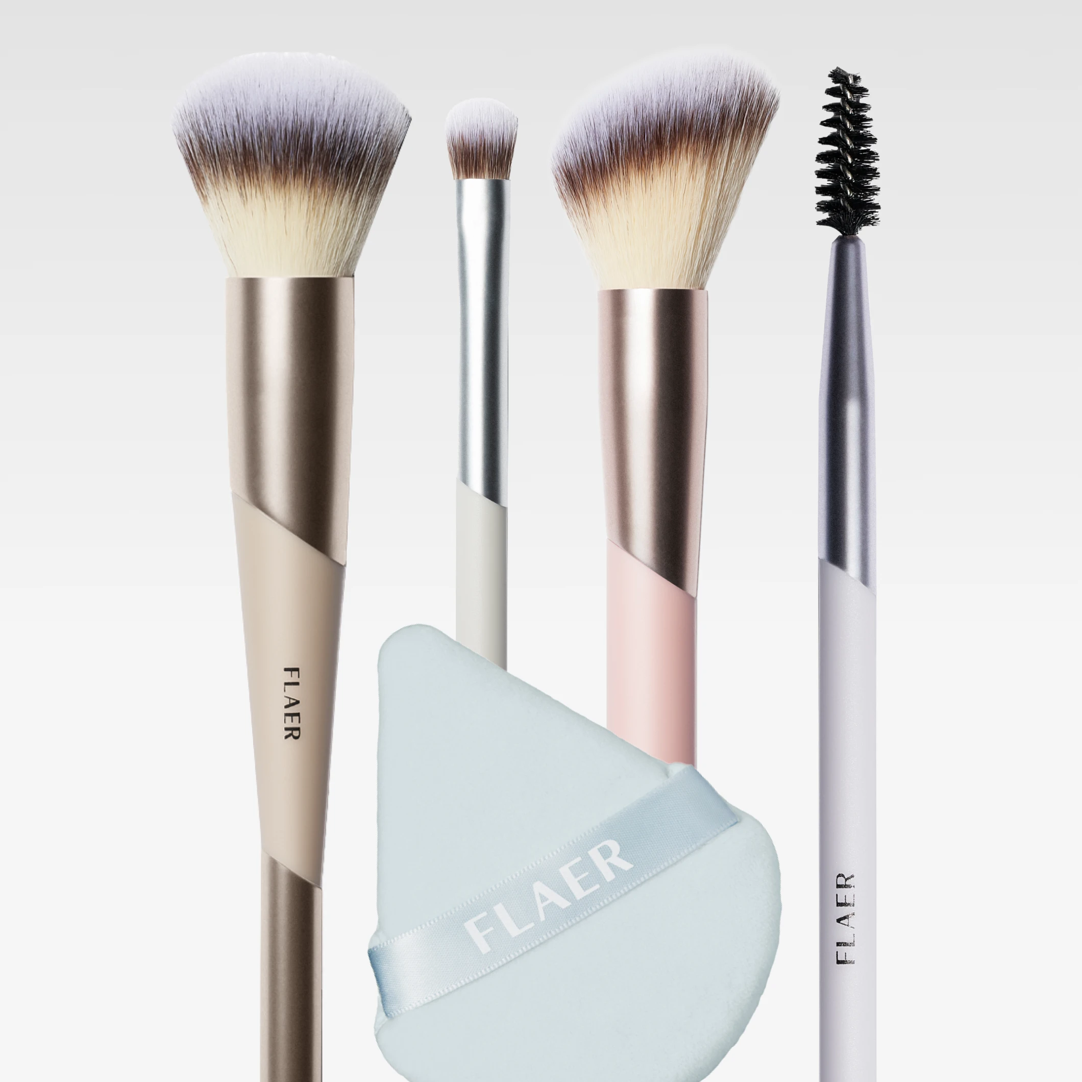 Sminkebørster og en makeupsvamp fra FLAER vises: pudderbørste, øyenskyggebørste, skrå børste og spooliebørste samt en lyseblå makeupsvamp med teksten “FLAER”.
