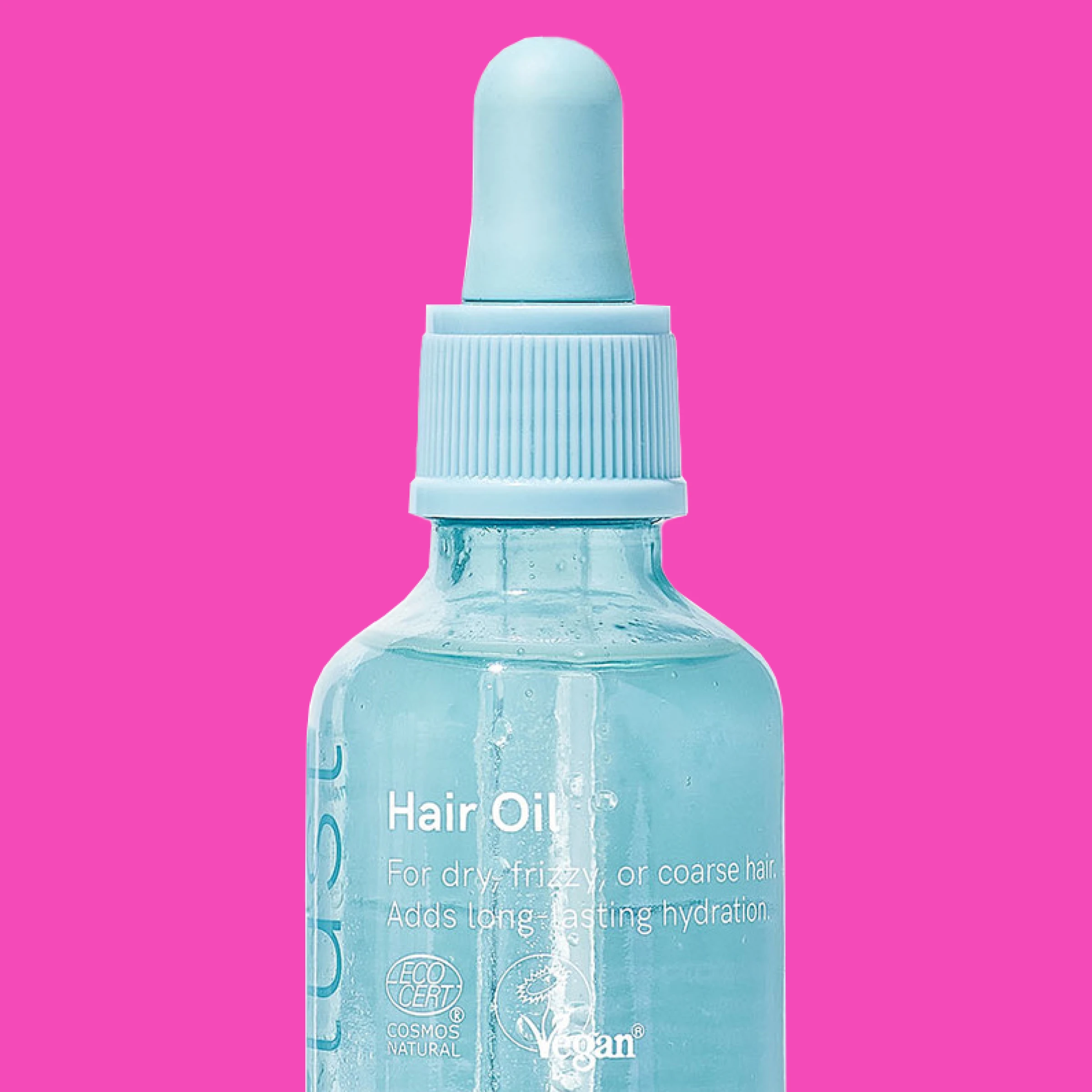 En lyseblå glassflaske med pipette fylt med hårolje mot rosa bakgrunn.