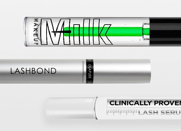 Nærbilde av vippeserum og mascara fra Olaplex og Milk Makeup med tekstene "Milk Makeup", "LASHBOND", "OLAPLEX" og "CLINICALLY PROVEN LASH SERUM" på emballasje i transparent og hvit design.