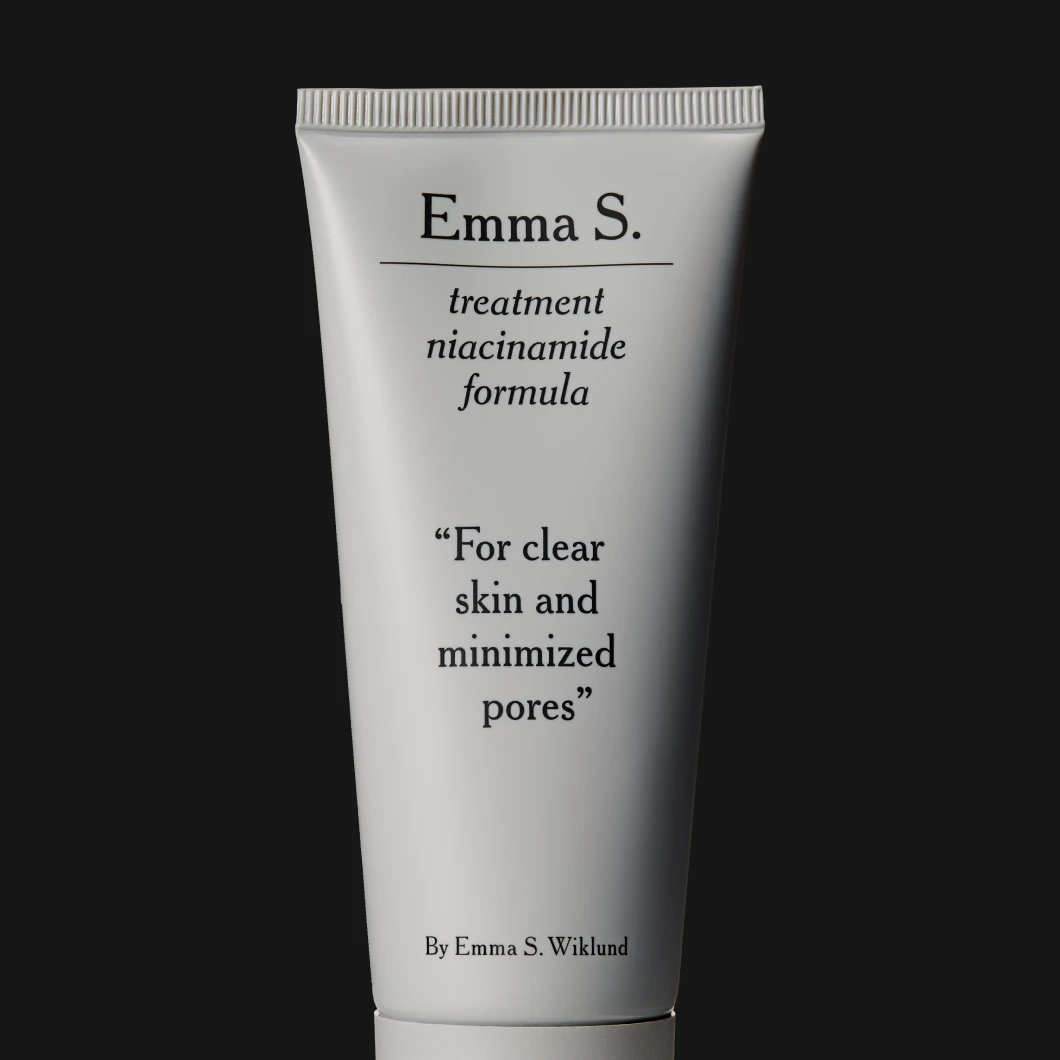 Tub med texten Emma S. treatment niacinamide formula mot svart bakgrund.