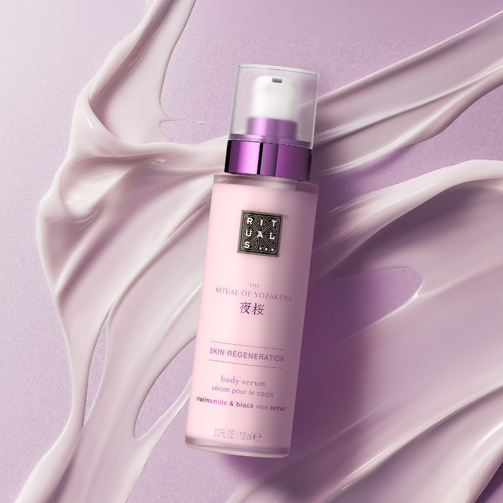 Rituals The Ritual of Yozakura Skin Regeneration body serum -pullo on asetettu vaaleanlilan voidemaisen tekstuurin päälle. Pullossa näkyvät Rituals-logo sekä tekstit “THE RITUAL OF YOZAKURA”, “SKIN REGENERATION”, “body serum” ja “niacinamide & black rice extract”.