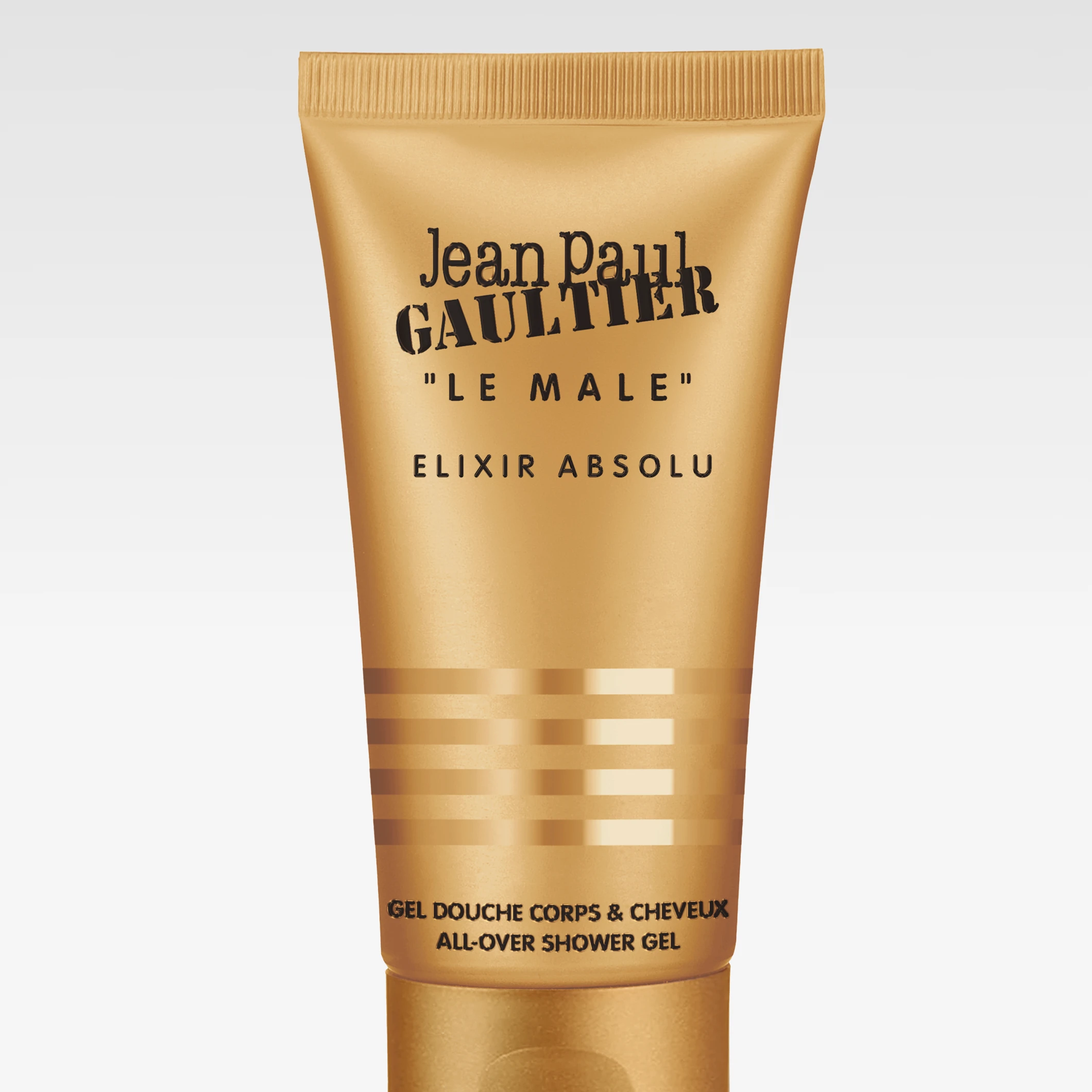 Gyllene tub med texten ”Jean Paul Gaultier Le Male Elixir Absolu”, avsedd för dusch och hår, fotograferad mot ljus bakgrund.