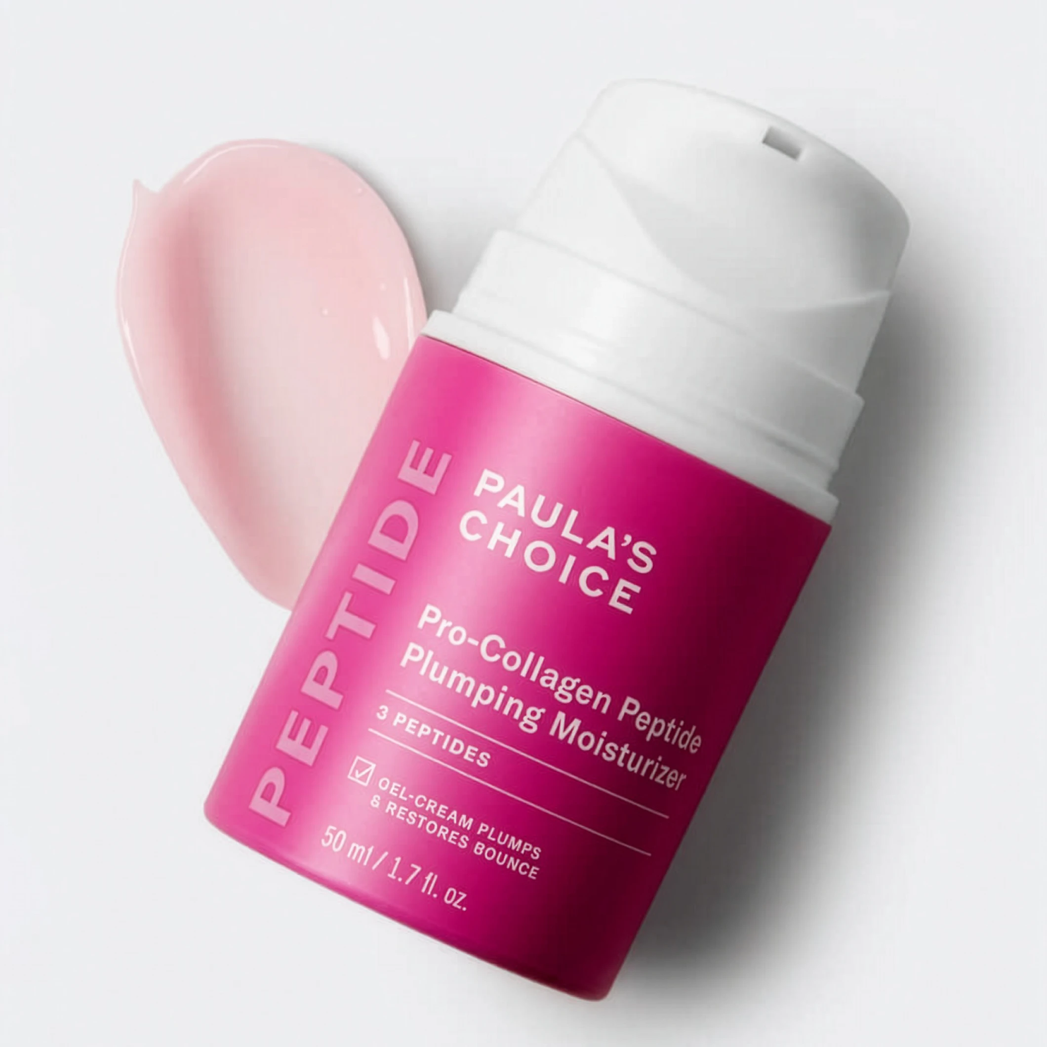Paula’s Choice Peptide Pro-Collagen Peptide Plumping Moisturizer -kasvovoide vaaleanpunaisessa pumppupullossa vaaleanpunaisen voidepisteen vieressä vaaleanharmaata taustaa vasten. Näkyvä teksti: ”PEPTIDE”, ”PAULA’S CHOICE”, ”Pro-Collagen Peptide Plumping Moisturizer”, ”3 PEPTIDES”, ”OIL-CREAM PLUMPS & RESTORES BOUNCE” ja ”50 ml / 1.7 fl. oz.”.