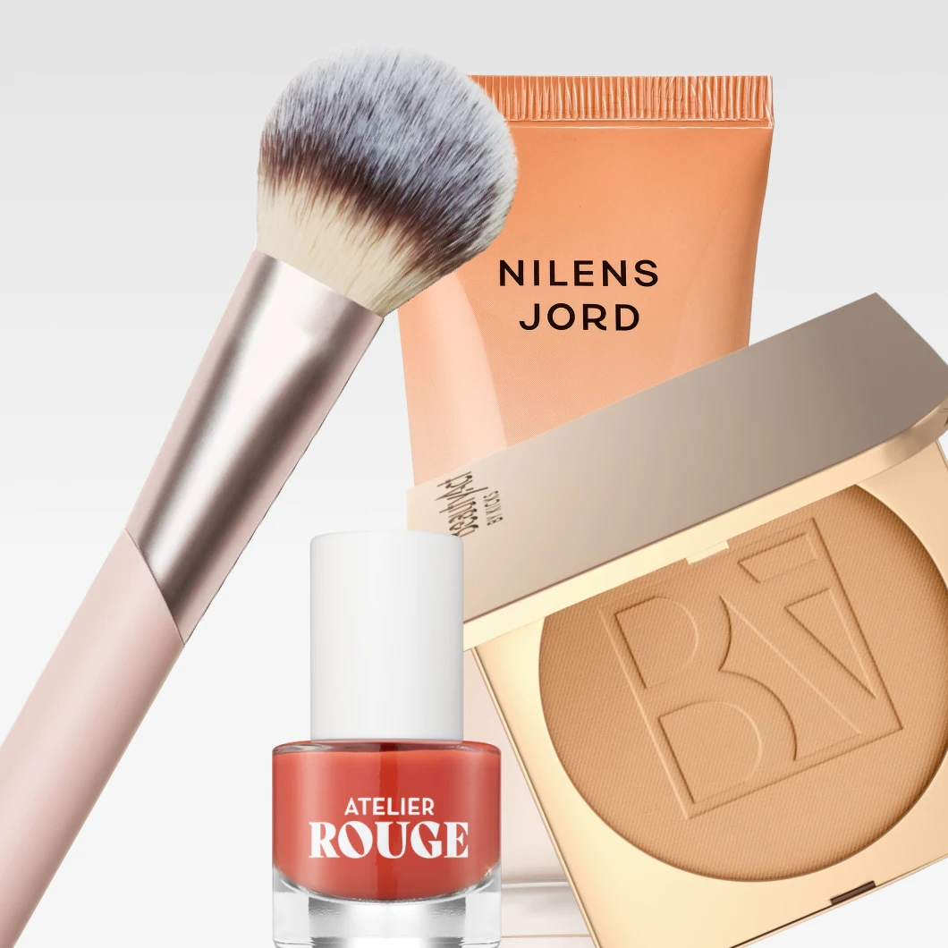 Vaaleanharmaata taustaa vasten esillä ovat Nilens Jord Hydra Glow SPF 15 Magic Tint Release Moisturiser, Atelier Rouge -kynsilakka, BeautyAct-puuteri ja meikkisivellin.