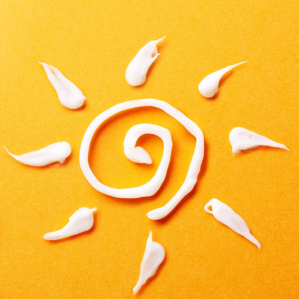 Solsymbol laget med solkrem på en gul bakgrunn.