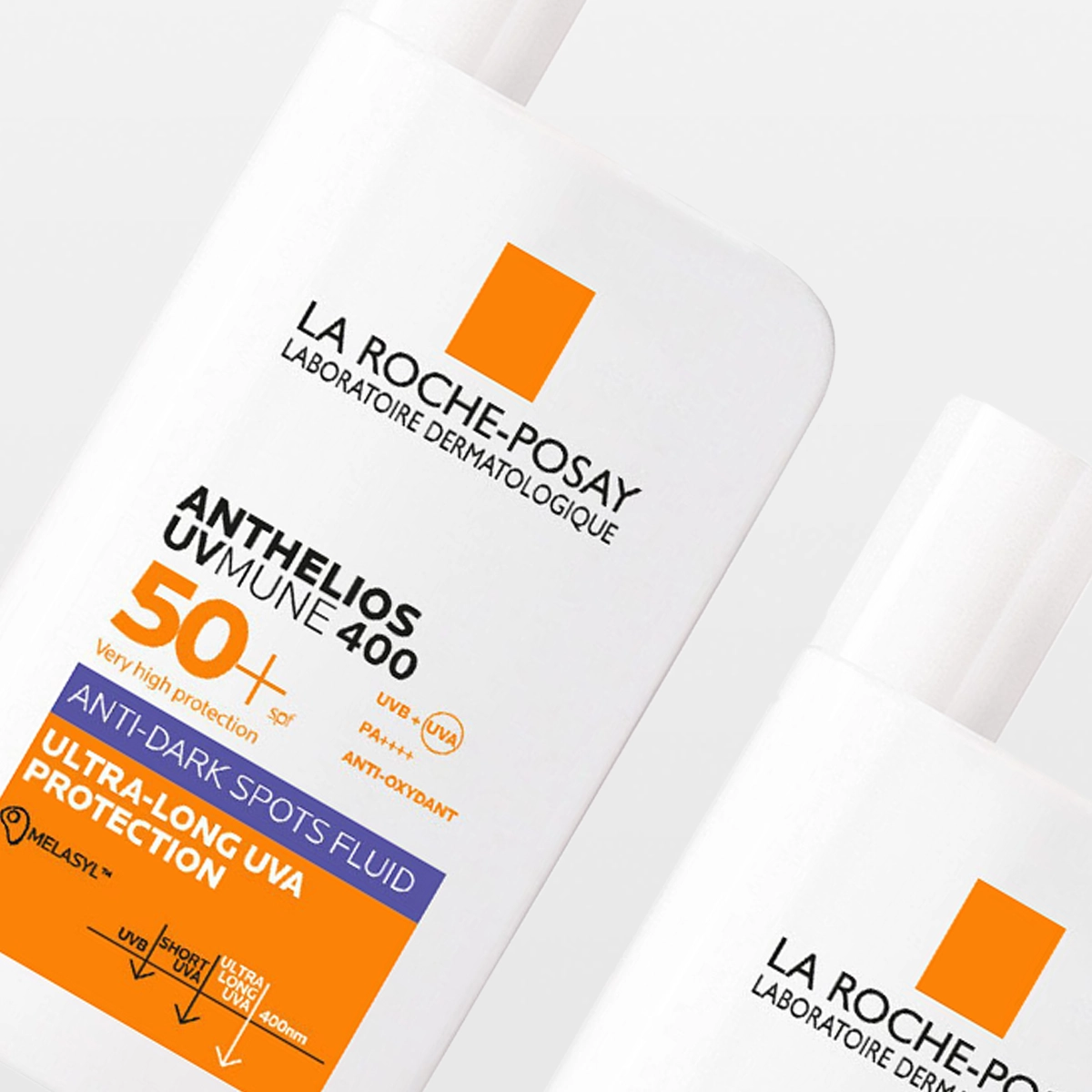 Två vita flaskor med solskyddet La Roche-Posay Anthelios UVMune 400 SPF 50+ syns mot ljus bakgrund. Förpackningen visar texten ”Very high protection 50+”, ”Anti-dark spots fluid” och ”Ultra-long UVA protection”.