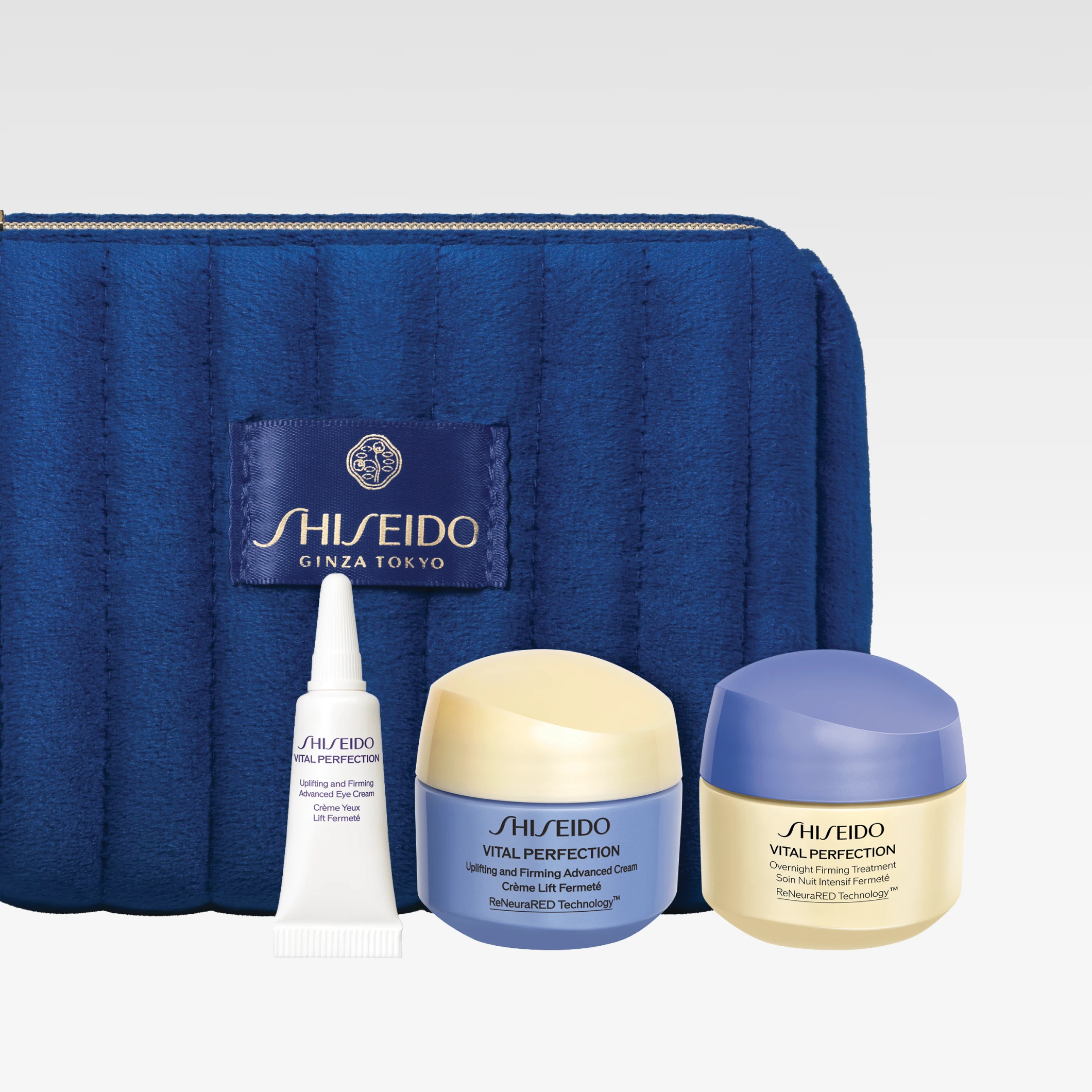 Shiseido hudpleiesett med blå toalettmappe merket “SHISEIDO GINZA TOKYO” og flere produkter inkludert “Vital Perfection” kremer og øyekrem i mindre størrelser.
