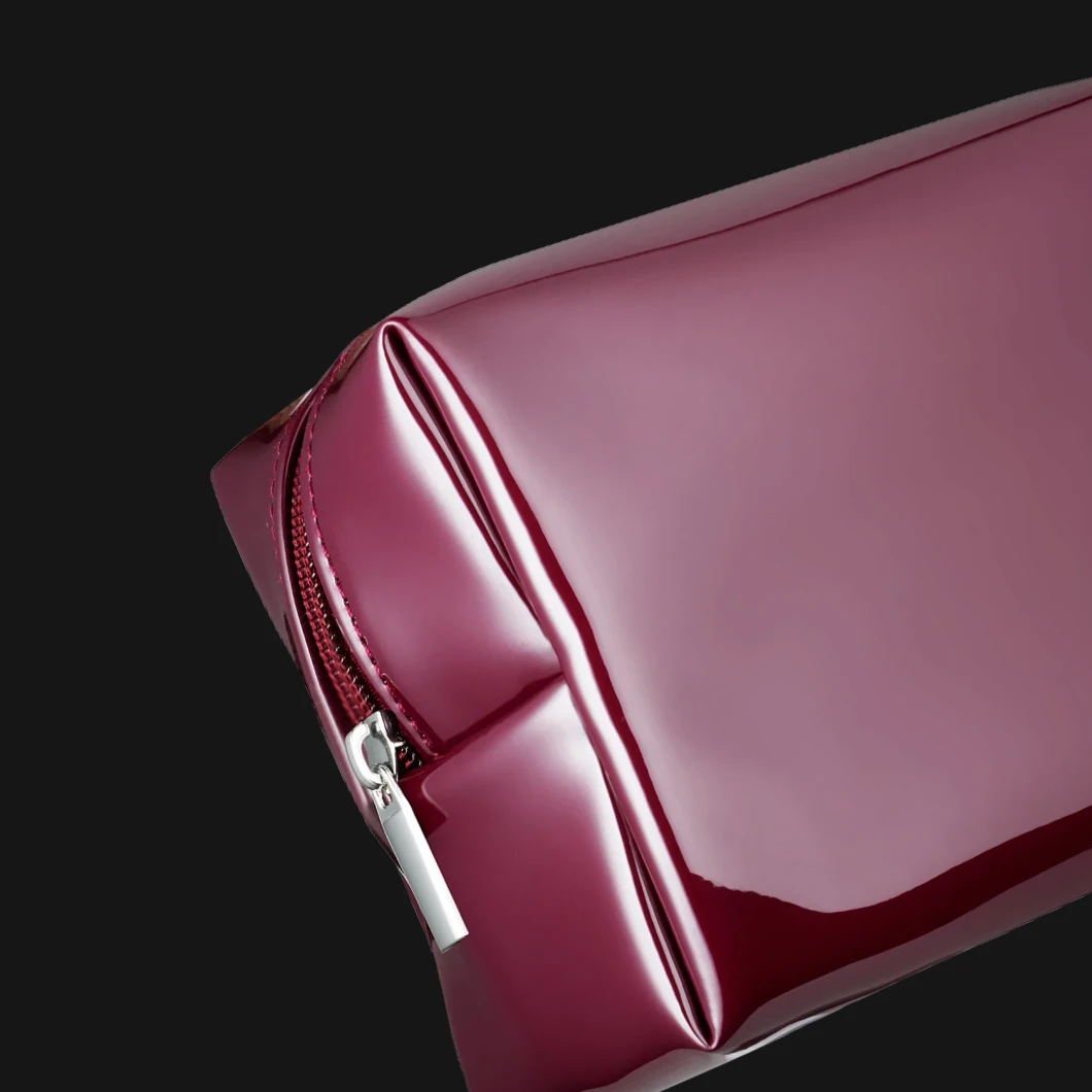  Et nærbilde av en blank vinrød veske med glidelås.