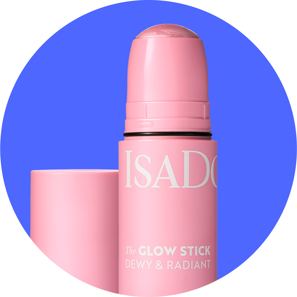 Kuva Isadora The Glow Stick Dewy & Radiant -korostuspuikosta. Vaaleanpunainen puikko, jossa on valkoista tekstiä. Taustalla sininen ympyrä.